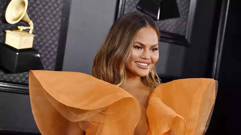 Chrissy Teigen and her daughter Luna, twins in leopard print swimsuits on a sailboat.