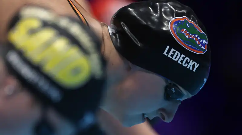 Olympic Kathleen Ledecky balances a glass of chocolate milk on her head while swimming