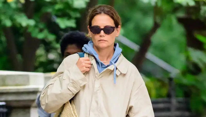 Katie Holmes styles khaki rain jacket with straw tote and $300 sneakers