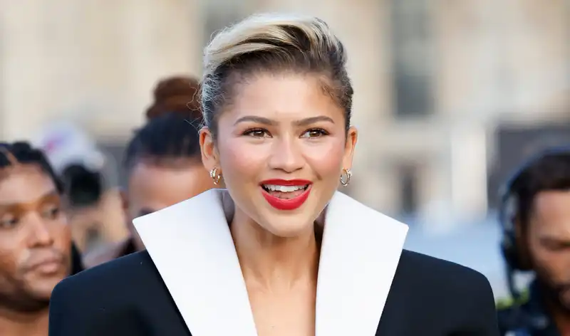 Zendaya matches her pocket square with red lipstick at Louis Vuitton's Paris Fashion Week show.